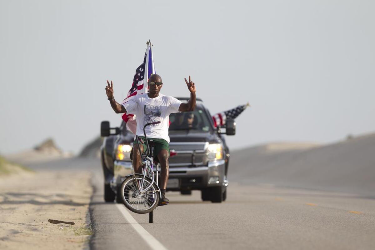 Rodney Hines of Raleigh, N.C, the “ No-Hand King” pedals on one wheel along NC 12 between sand dunes in the Pea Island Wildlife Refuge on Tuesday June 16, 2015 in the Cape Hatteras National Seashore on the North Carolina Outer Banks. Hines was attempting to ride on one wheel from Nags Head to Buxton. After a fall, and several episodes of cramping, Hines stopped his ride after approximately 31 miles.
