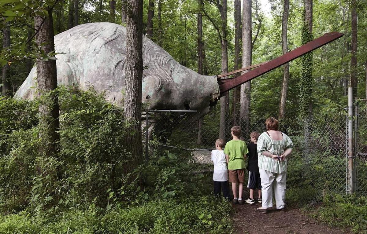 Jennifer Lemons and her children stare silently at the brontosaurus on the old dinosaur trail in 2009, after vandals took the head off. It was restored after Durham’s Northgate Park community rallied to pay for repairs.