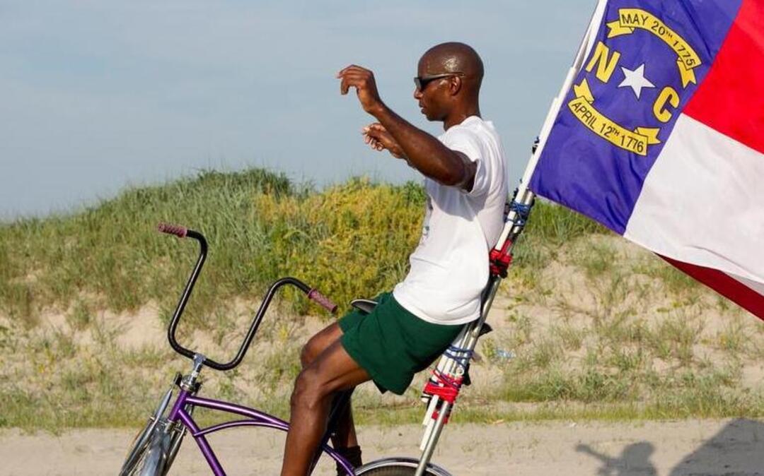 Rodney Hines of Raleigh, N.C, the “No-Hand King” pedals along NC 12 between sand dunes in the Pea Island Wildlife Refuge on Tuesday June 16, 2015 in the Cape Hatteras National Seashore on the North Carolina Outer Banks. Hines was attempting to ride on one wheel from Nags Head to Buxton. After a fall, and several episodes of cramping, Hines stopped his ride after approximately 31 miles.
