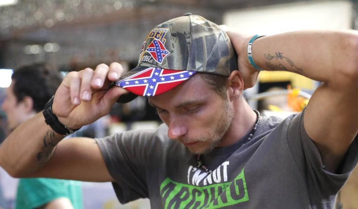 Fairgoer Andrew Bird tries on a hat that he bought at the Sons of Confederate Veterans booth at the N.C. State Fair in Raleigh on Oct. 19, 2017. They were also giving away stickers of the battle flag and talking about Southern history. Volunteers working at the booth say they give away thousands of the stickers every day.