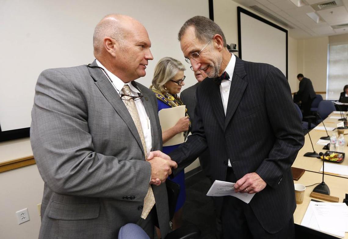 UNC Board of Governors chair Harry Smith, left, congratulates Dr. William Roper after he was named UNC system interim president at the UNC Board of Governors meeting at the UNC Center for School Leadership Development in Chapel Hill, N.C., Thursday, Nov. 1, 2018. UNC President Margaret Spellings is in the background.