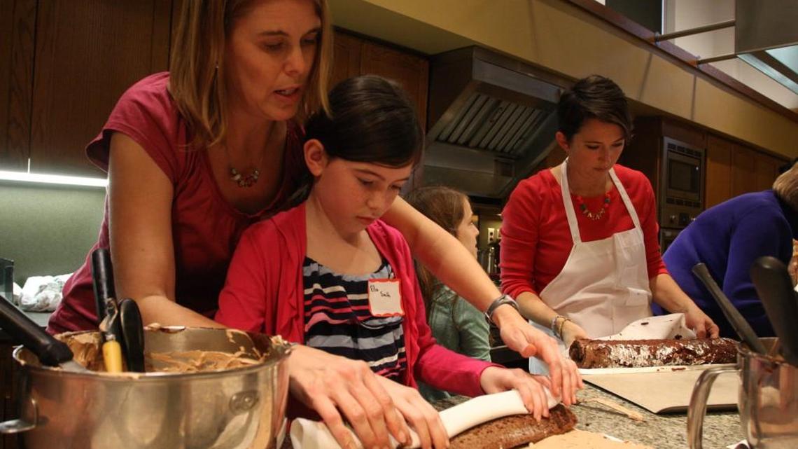 Ella Smith, 9, in the striped shirt, and her mother, Kristi Smith, roll their yule log after filling it with frosting Sunday, Dec. 20, 2015 during a class at Southern Season.