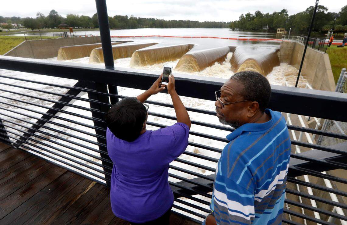 Majorie and David Baggett of Fayetteville check out the water rushing the weirs of the Hope Mills Dam in Hope Mills, N.C., Sunday, Sept. 16, 2018. The dam empties into the Cape Fear River.