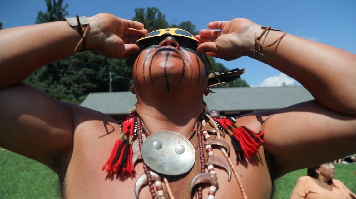 Bo Taylor, in full ceremonial Cherokee dress, watches the solar eclipse progress during a gathering at the fairgrounds in Cherokee, NC on Monday, Aug. 21, 2017.