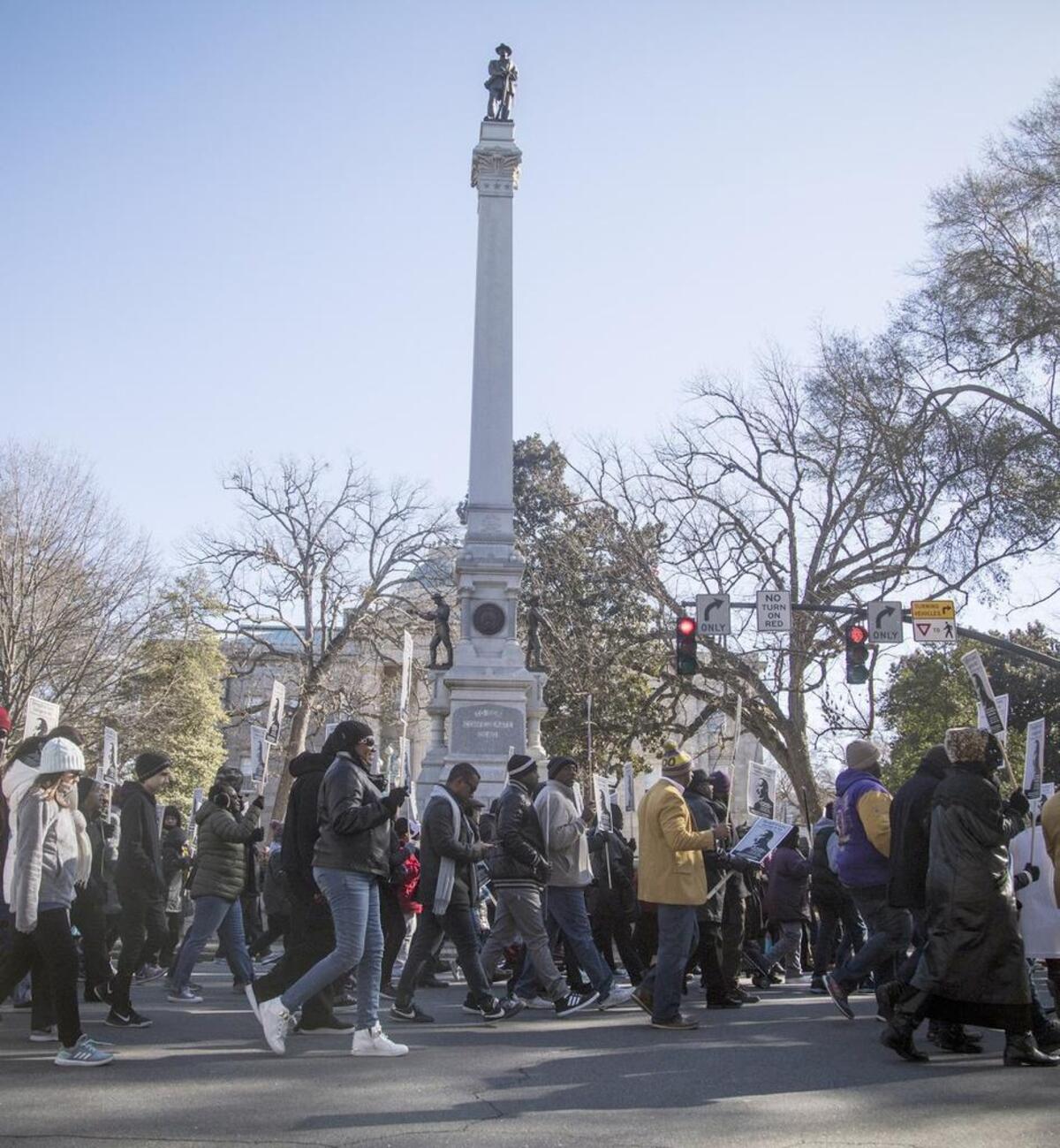 Hundreds march pass a confederate monument at the North Carolina State Capitol while marching in honor of Dr. Martin Luther King Jr. Monday morning, Jan. 15, 2018 in downtown Raleigh during the annual MLK Memorial Day March.
