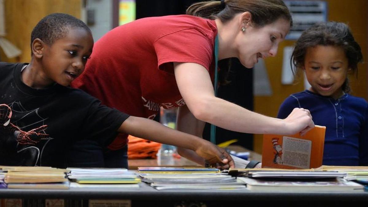 Amanda Weatherly helps Mariah Barbee picks out a Dr.Seuss book as Shamar Manns reaches to grab a book for himself during the Book Harvest event at Carrboro Elementary School in June. Book Harvest’s founder creates its success to the help she received from the Executive Service Corps.