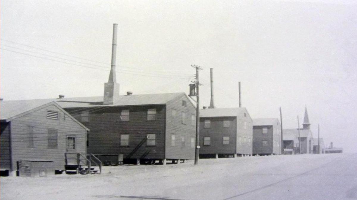 A row of wooden barracks at Camp Butner during World War II. One of the base’s five chapels is visible in the distance.