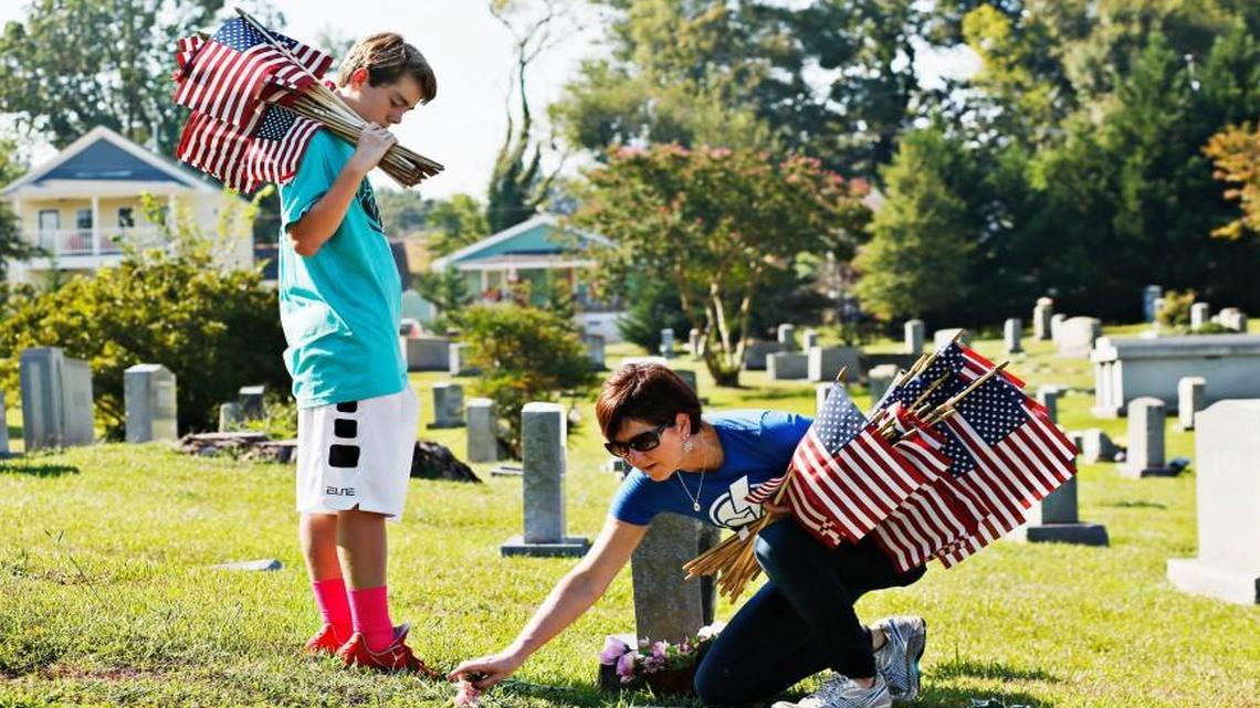 Kay Davis, right, and her 12-year-old grandson, Jack Davis, left, are among several volunteers placing hundreds of American Flags on the graves of veterans at Oakwood Cemetery last Sept. 9 in advance of the cemetery’s 9/11 Service of Remembrance & Appreciation.
