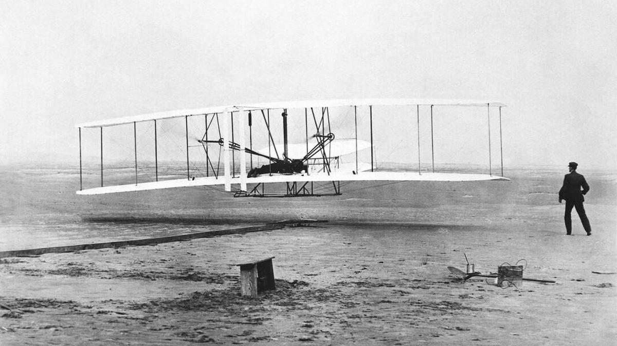 As Wilbur Wright looks on, brother Orville pilots the Wright Flyer in its historic flight of Dec. 17, 1903, at Kitty Hawk, N.C.
