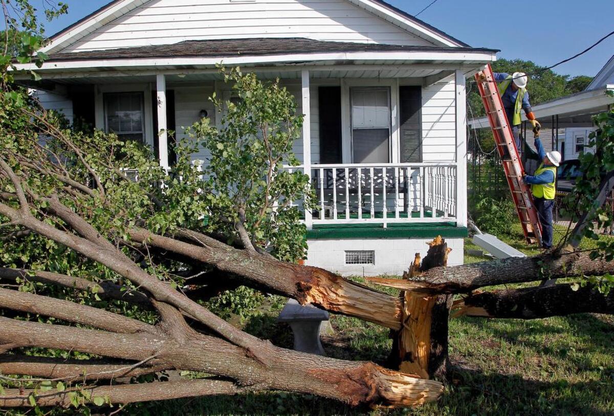 Duke Energy’s Jason Pearce, top, and Brandon Hicks repair a power line to a home in Beaufort after it was downed by a fallen tree during Hurricane Arthur on July 4, 2014.