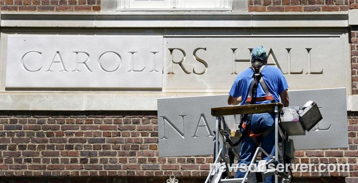 Sign installer Roger Phillips of Broach Custom Signs in Wendell, NC slowly rises with the second urethane panel of the new Carolina Hall nameplate Thursday afternoon, August 13, 2015 to cover the old Saunders Hall name on the UNC-CH campus. After an outcry over the personal history of the 19th century UNC alumnus William L. Saunders the university decided recently to change the name to Carolina Hall, removing all vestiges of the old name.