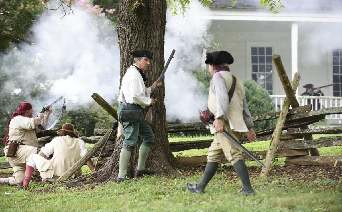 Jim Van Ness shields behind a tree as he reloads his gun during a re-enactment of the House in the Horseshoe Battle near Sanford, N.C., on Sunday, August 7, 2016. Volunteers re-enacted the 1781 fight between British Loyalist David Fanning and Patriot Phillip Alston and their men as part of the weekend’s festivities.