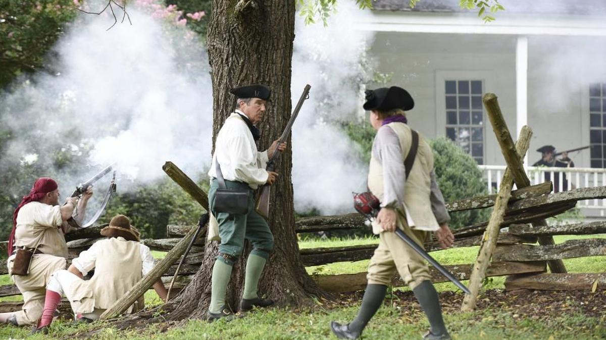 Jim Van Ness shields behind a tree as he reloads his gun during a re-enactment of the House in the Horseshoe Battle near Sanford, N.C., on Sunday, August 7, 2016. File photo.