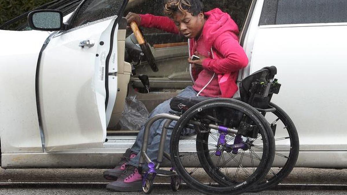 
Latisha Anderson maneuvers into her wheelchair in the rain outside the downtown library in Greensboro. Anderson, who was paralyzed after a gunshot wound, is a nurse who was hired by Central Prison after a phone interview. When jail officials discovered she uses a wheelchair on the day of her orientation, they reneged on the contract. Anderson filed a complaint with the governor’s office and sent out a stream of emails, explaining that she works hard and desperately needs income to avoid living in a shelter. Eventually, the prison called her back. She starts working there Monday, March 16.
