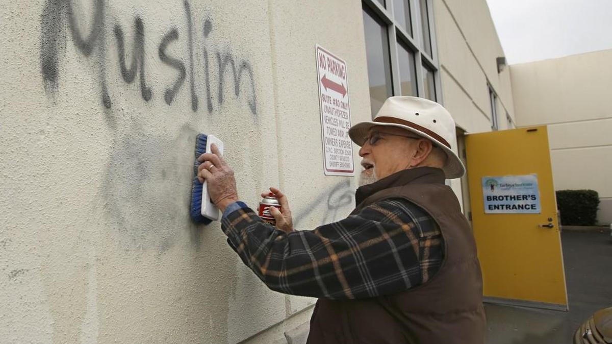 In this Feb. 1, 2017 file photo, Tom Garing cleans up racist graffiti painted on the side of a mosque in what officials are calling an apparent hate crime in Roseville, Calif. California’s attorney general says the number of hate crimes increased about 11 percent last year, the second consecutive double-digit increase after years of decline. The report released Monday, July 3, 2017, shows 931 hate crimes statewide in 2016, nearly 100 more than in 2015.