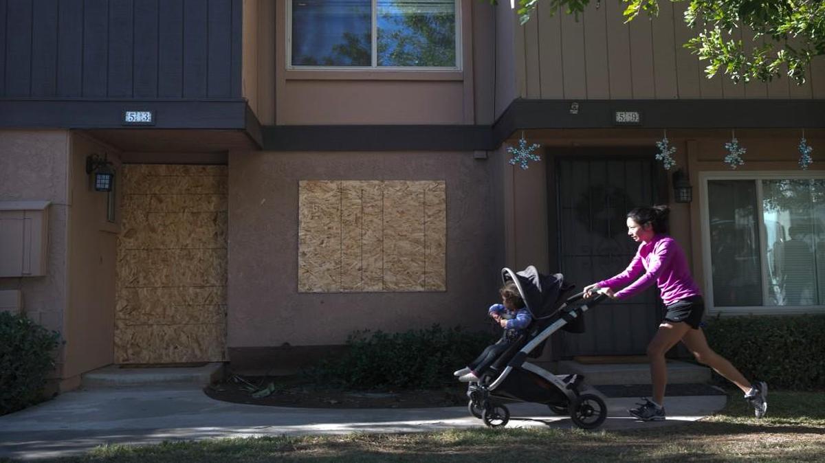 A woman pushes a baby stroller past the boarded-up townhouse rented by San Bernardino shooting rampage suspects Syed Farook and his wife, Tashfeen Malik in Redlands, Calif. The Pakistani woman who joined her U.S.-born husband in killing multiple people in a commando-style assault on his co-workers is at the center of a massive FBI terrorism investigation, yet she remains shrouded in mystery.