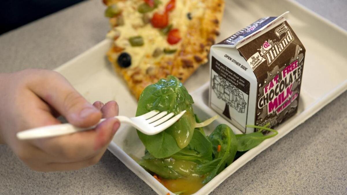 
Zach Cobb, 11, prepares a bite of spinach and romaine lettuce salad with a pizza featuring whole grain crust and reduced fat cheese.
