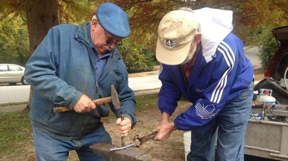 Larry Martin, left, and Marty Miller, from Harrisonburg, Va., use blacksmithing tools to shape a piece of gun metal into a garden implement at Raleigh Mennonite Church on Sunday, Nov. 12, 2017.