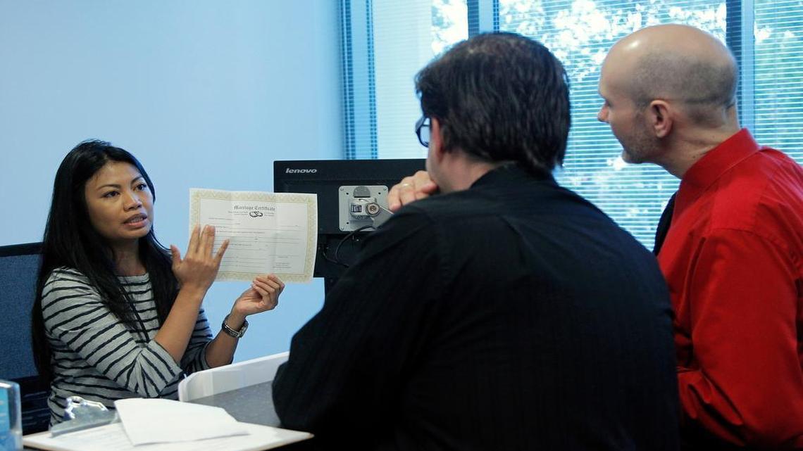 
Phoebe Mendoza with the Wake County Register of Deeds office, left, explains the process to same-sex couple Craig Johnson, center, and Shawn Long as they get a marriage license in downtown Raleigh on Oct. 13, 2014. The N.C. House is delaying a veto override vote on a bill that would allow magistrates and register of deeds employees to opt out of marriage duties on religious grounds.
