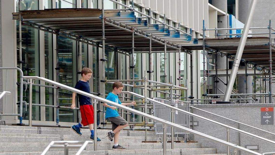 
Two boys walk past a myriad of fences and scaffolding as they leave the Museum of Natural Sciences Nature Research Center Building in Raleigh on April 20, 2015. Scaffolding and fences protect people below from the possibility of falling debris. Both the museum and their neighbor, the State Employees Credit Union, have experienced problems with large panes of glass installed in the buildings 
