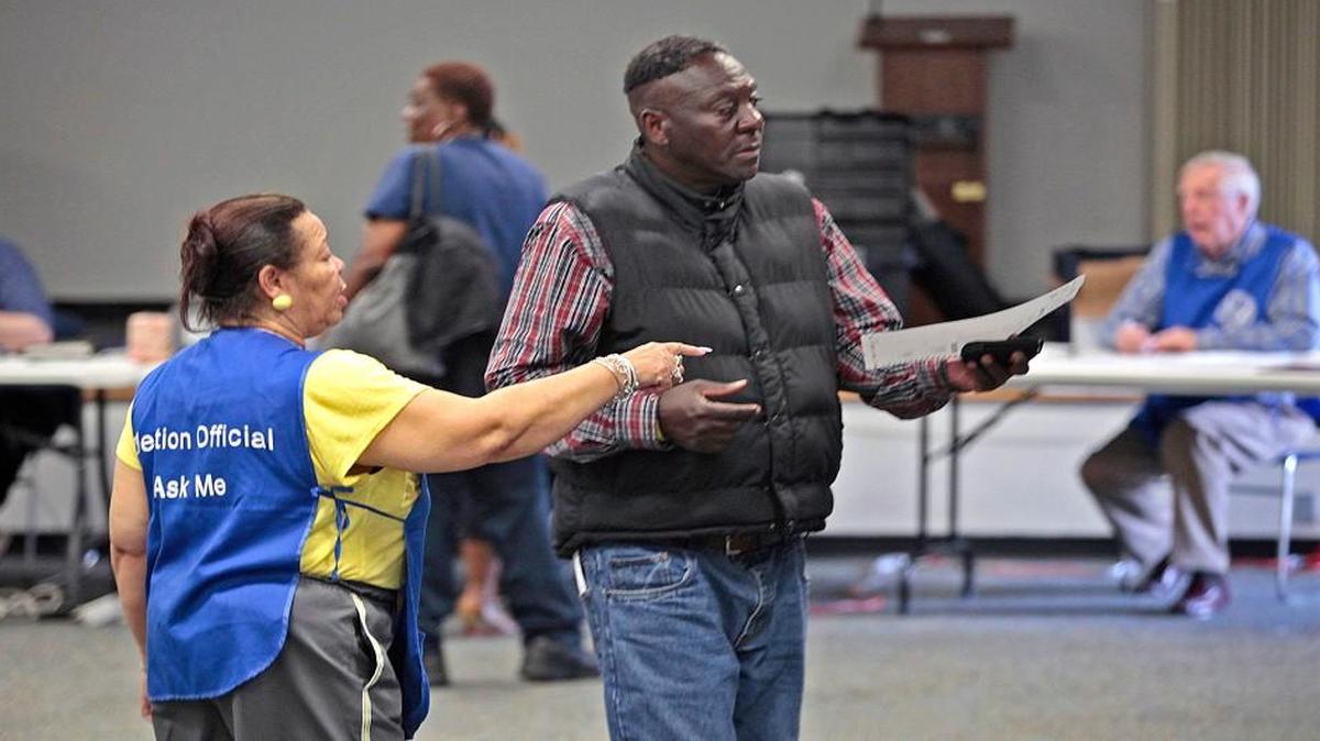 A poll worker at the Durham Main Library directs a voter with his ballot to an open voting space during early afternoon voting the Durham County Main Library precinct Tuesday, March 15, 2016.
