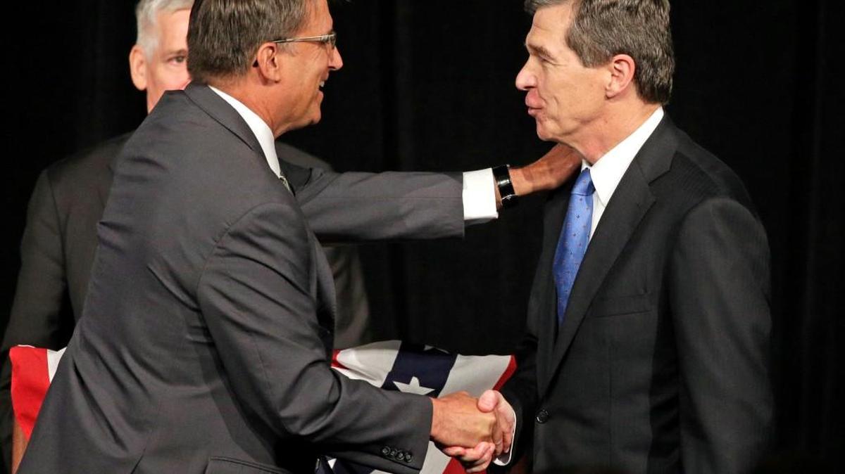 North Carolina Gov. Pat McCrory, left, shakes hands with North Carolina Attorney General Roy Cooper, right, after a candidate forum in Charlotte, N.C., Friday, June 24, 2016. The two men will face each other in November for governor in what could be the most expensive and watched gubernatorial election this year.