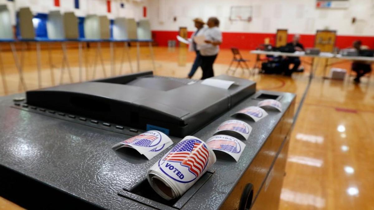Two Durham NC voters at center move toward the voting booths after getting their ballots during primary day voting Tuesday mid-morning, June 7, 2016 at the Pearsontown Elementary School precinct in southeastern Durham, NC. Pearsontown precinct Chief Judge Michael Williams said that 50 voters had cast ballots by 10am Tuesday out of a total over about 3,000 registered voters there. This was not taking into account the absentee and early voters who had already cast ballots.