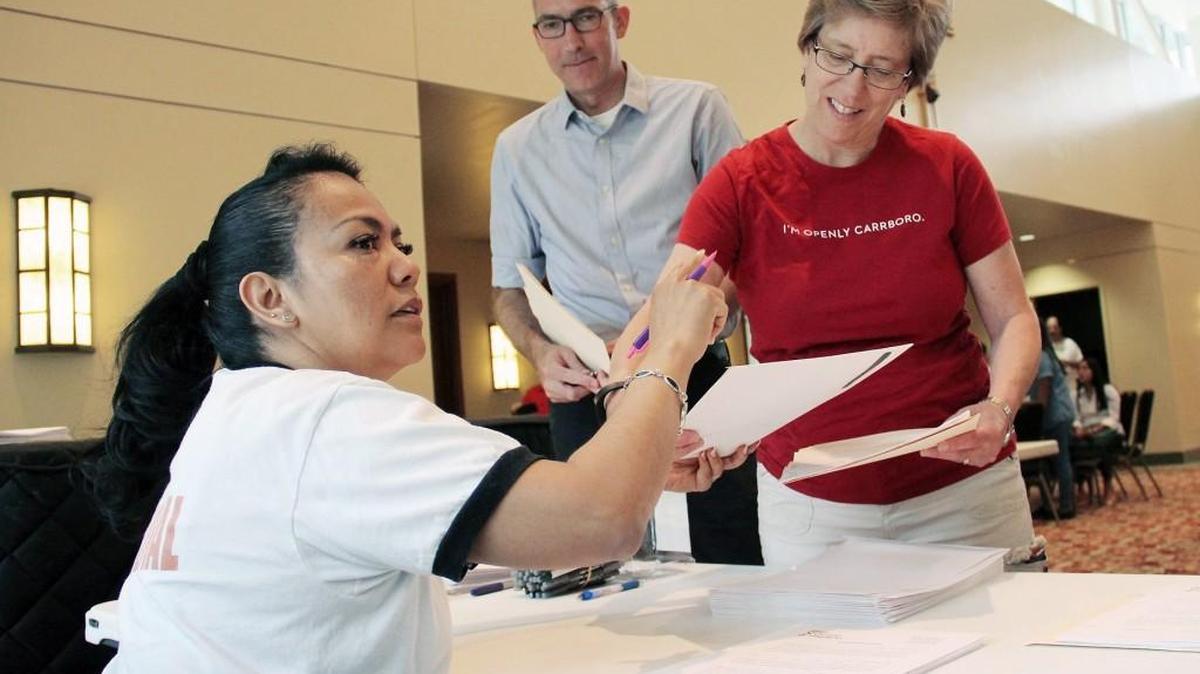 Carrboro Mayor Lydia Lavelle (in red shirt) and Alderman Damon Seils sign up for Faith ID cards Saturday, June 24, 2016, at St. Thomas More Catholic Church in Chapel Hill. The cards provide a form of identification for those without other forms of photo ID recognized in North Carolina. El Centro Hispano enrolled about 75 people in the program Saturday.