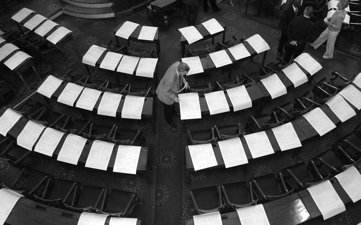 In this April 2011 News & Observer file photo, a staffer places copies of the Halifax Resolves on the desks of House members before a special session held in the old House chamber of the Capitol in Raleigh. They were celebrating the Resolves, a forerunner of the U.S. Declaration of Independence. On the other side of the building, the state Senate voted to pardon former Gov. William Holden, who was impeached in the 19th century.