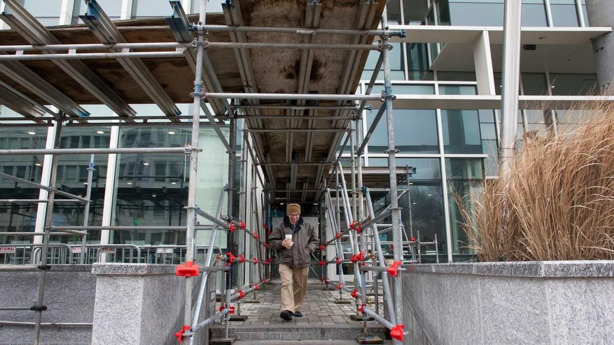 Don Williams leaves the Daily Planet Cafe at the North Carolina Museum of Natural Sciences beneath scaffolding on Friday, February 3, 2017 in Raleigh, N.C. The scaffolding has been in place for several years to protect pedestrians from cracking and falling glass.