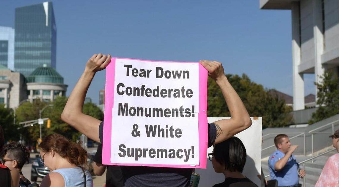 A protester holds a sign outside of the State Archives building during a meeting of the NC Historical Commission Friday morning, Sept. 22, 2017. The commission voted 9-1 to postpone a decision on moving Confederate monuments from Raleigh the Bentonville battleground in Johnston County.