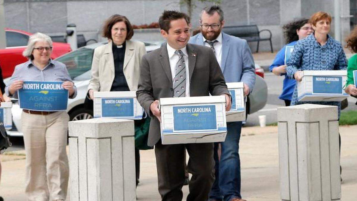 
Chris Sgro, center, with Equality NC leads a group of about 15 protestors as they deliver petitions to the Administration Building on Jones St. in downtown Raleigh on April 20, 2015 asking Gov. Pat McCrory to veto the two religious freedom (RFRA) bills being considered by the General Assembly. Some of the boxes are empty; they said that they "symbolized" the number of petitions. 
