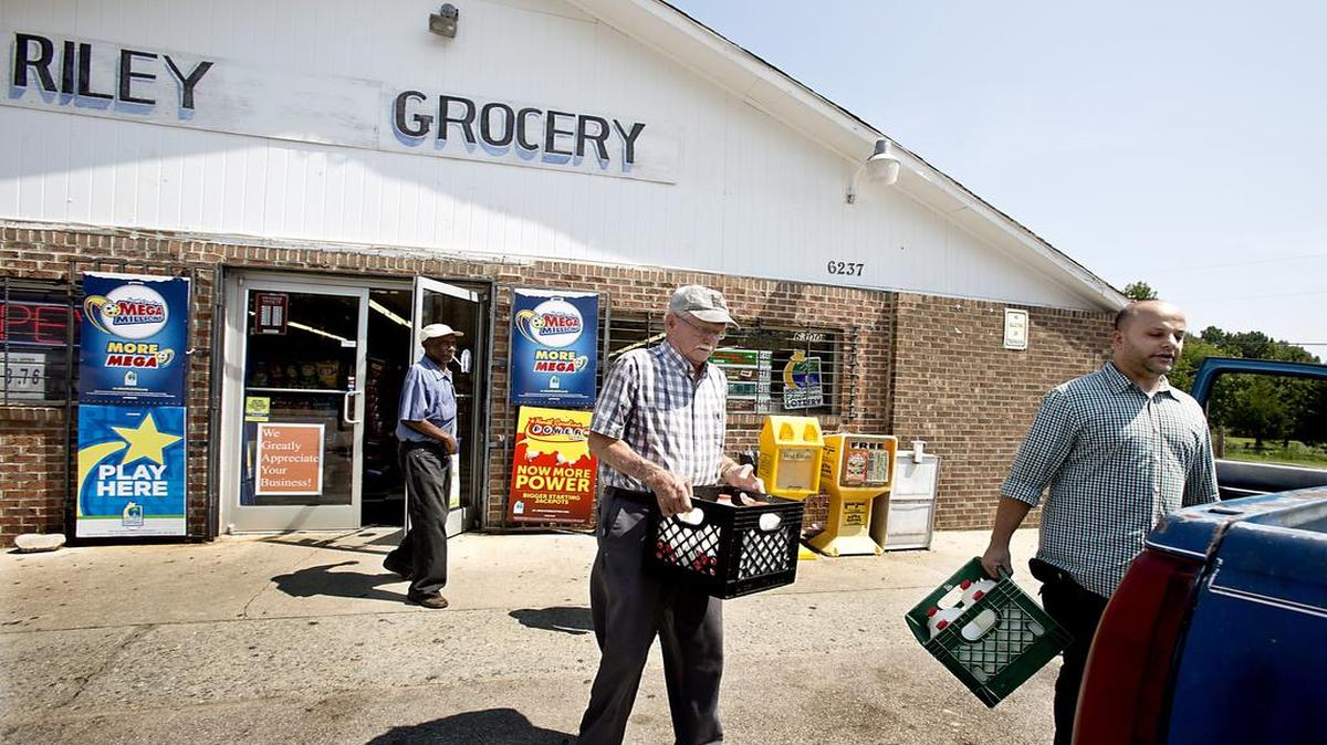 
Ray Carroll, center, and William Bradford, left, both of Raleigh, get some help loading crates of milk onto the back of their truck from Riley Mart store manager Sam Sammour near Wendell. A proposed grant program would put fresh fruits and vegetables in corner stores located in “food deserts.”
