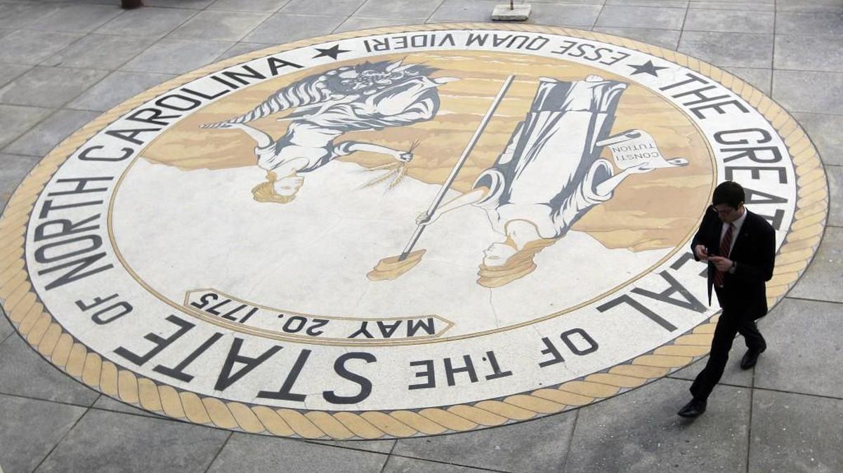 A man walks alongside the the big state seal that is at the entrance to the Legislative Building in Raleigh, NC on Jan. 23, 2013.