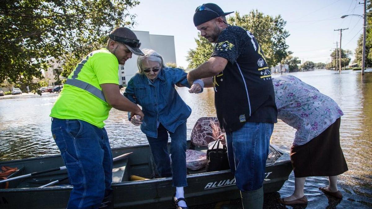 Shirley Walters, 81, center is helped from a john boat with her daughter Sharon Walters, right, by Graham Melvin, second from right and an unidentified man left, after flood waters threatened the Walters's home after Hurricane Matthew caused downed trees power outages and massive flooding Monday, October 10, 2016 in Lumberton, NC.
