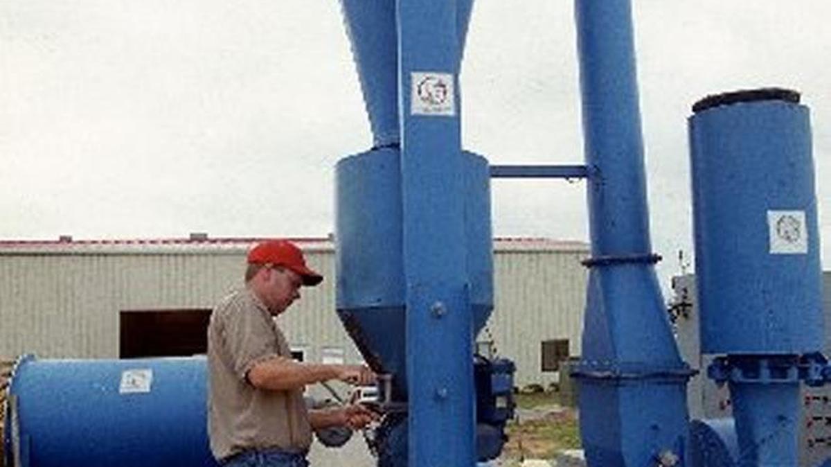 A worker at the NCSU Waste Management labs in Raleigh does maintenance work on a flash dehydrator, which is used to quick-dry animal waste.