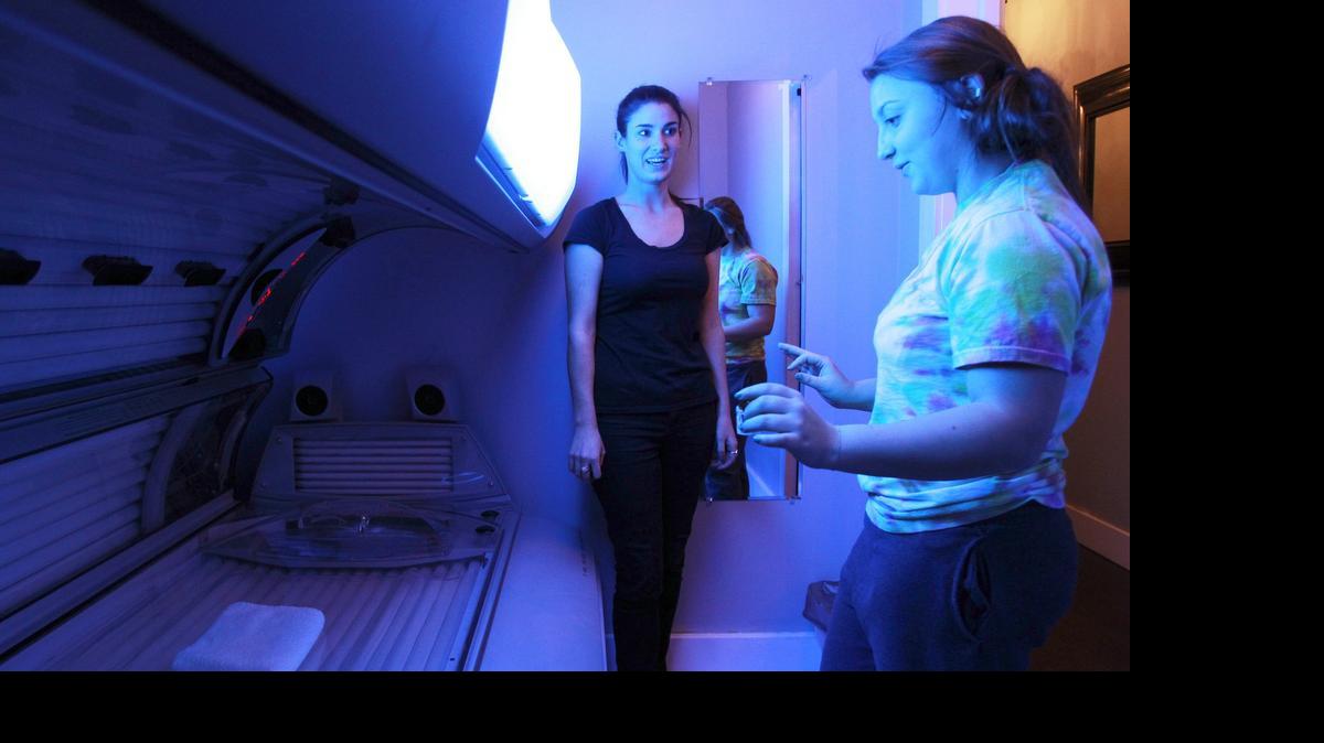 
Sarah Baumeister, left, general manager at Jill's Beach Luxury Tanning, shows Lindsy Weeks, 16, how to use a tanning bed in 2013. The N.C. Senate voted Wednesday to ban anyone under age 18 from using a tanning bed.
