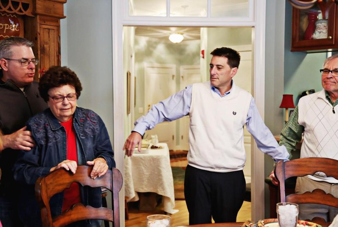 Brad Woodhouse, left, puts his mom, Joyce, in the middle to hold younger brother, Dallas', hand as the family joins together for a prayer at Joyce's Raleigh home on Thanksgiving, Nov. 23, 2017.