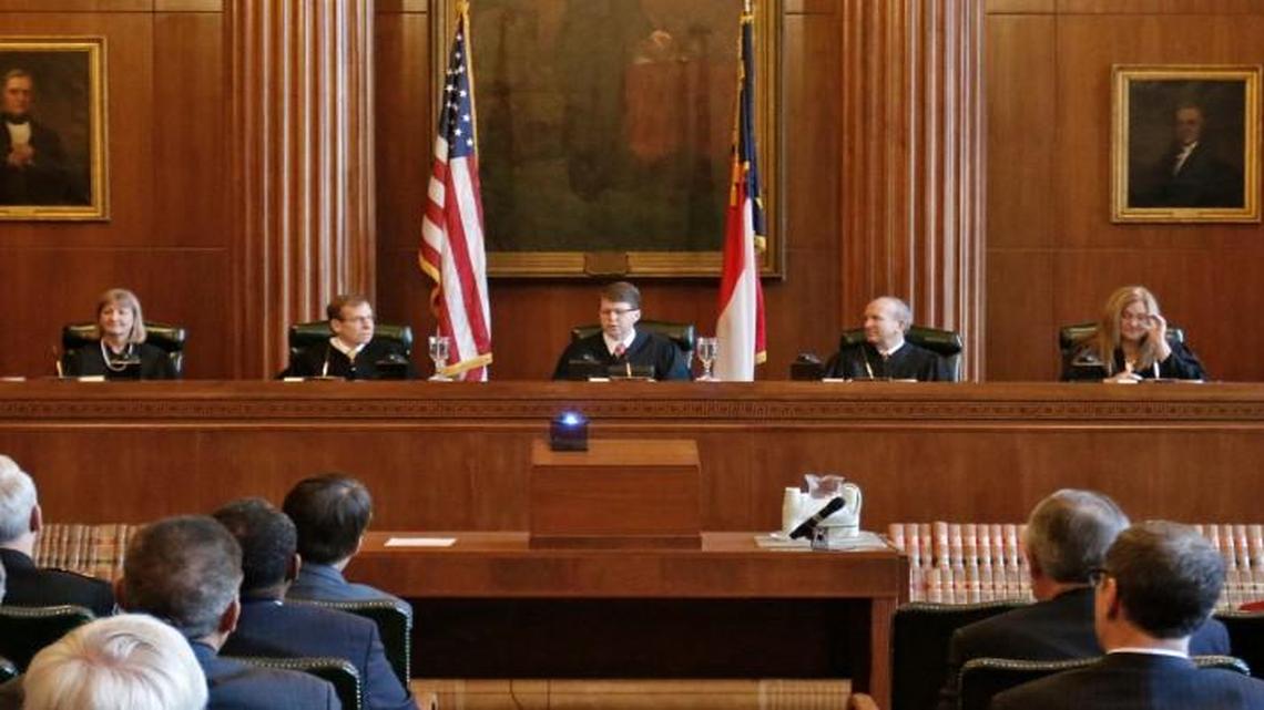 L to R: Supreme Court of North Carolina Justices Cheri Beasley, Robin Hudson, Robert Edmunds, Jr., new Chief Justice Mark Martin, Paul Newby, Barbara Jackson and Sam Ervin IV listen to the opening remarks of newly sworn in Chief Justice Mark Martin, center on Jan. 5, 2015, in Raleigh. Martin was appointed to fill the term of a retiring Chief Justice of NC, and won election recently to a full eight-year term of office.