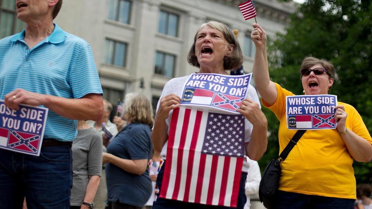 
Rebecca Burmeister of Raleigh shows her support at a Monday rally at the Capitol. NAACP President William Barber II called on Gov. Pat McCrory to abolish the state-issued Confederate battle flag license plate and chastised lawmakers for a bill protecting monuments. McCrory, who signed the monuments bill into law, says legislators must act to ban flag plates.
