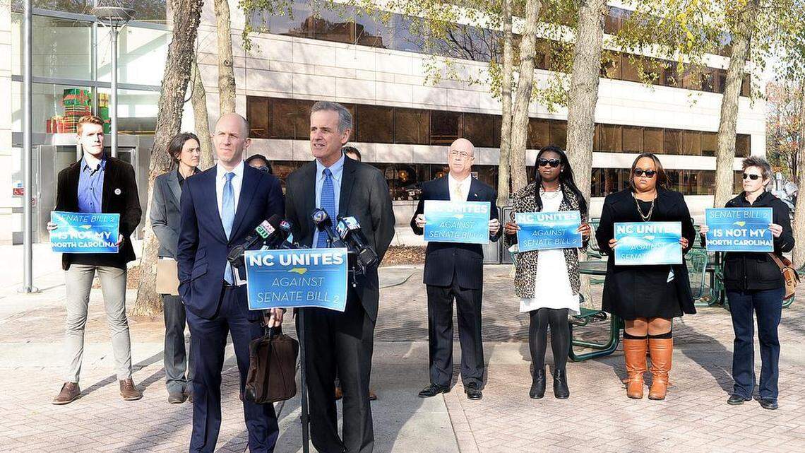 Jake Sussman, left front, and Luke Largess speak at a press conference Wednesday morning at the Government Center about their new challenge to a state law that allows local officials to opt out of sworn duties on religious grounds.