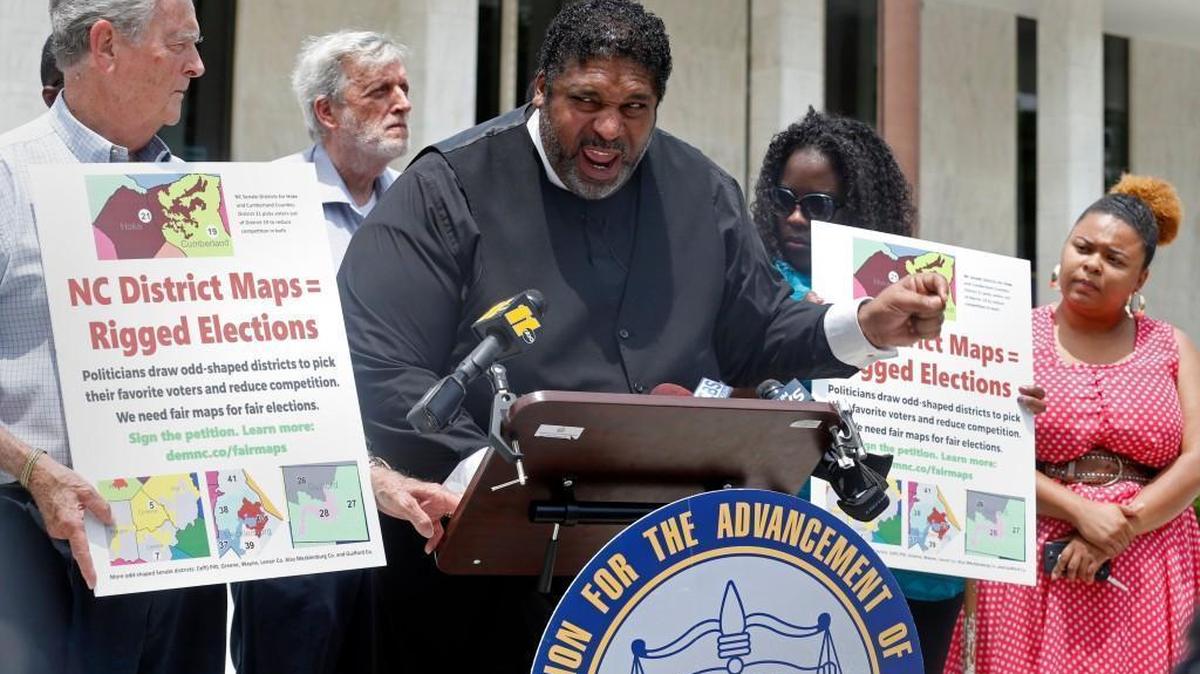 About a dozen protestors flanked Rev. William Barber, center, as he held a press conference in front of the Legislative Building in Raleigh, NC, on June 13, 2017. He called for the General Assembly to stop making laws until legislative districts could be redrawn following a U.S. Supreme Court ruling that said they were unconstitutional.