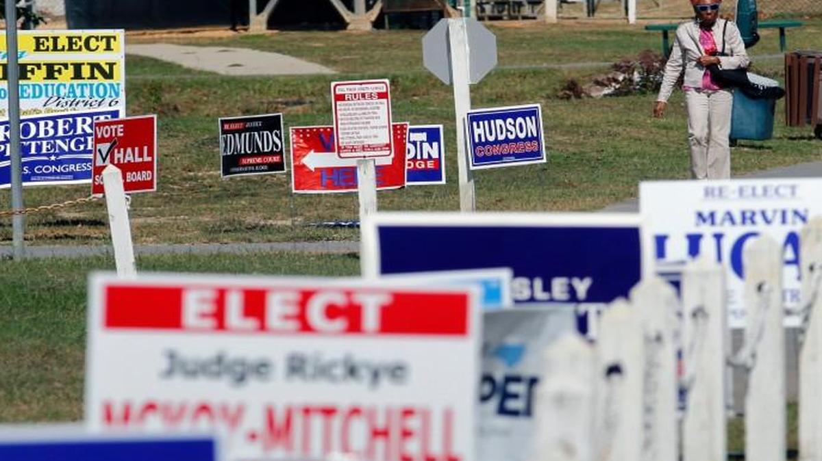 A voter navigates through a sea of election signs as she joins hundreds of others who came out on the first day of early voting at the Hope Mills Recreation Center in Hope Mills in October. ,