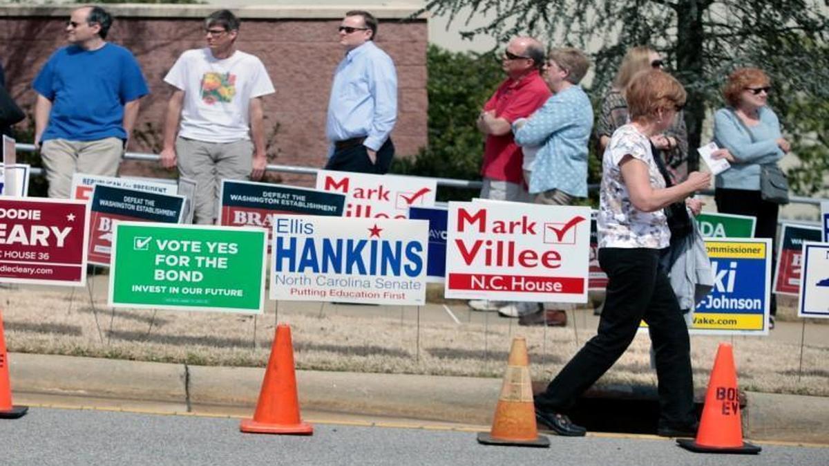 Two Wake county voters in foreground leave the early voting precinct while others wait in line to vote, background, outside of the Herbert C. Young Community Center early voting site in Cary, NC Friday, March 11, 2016.