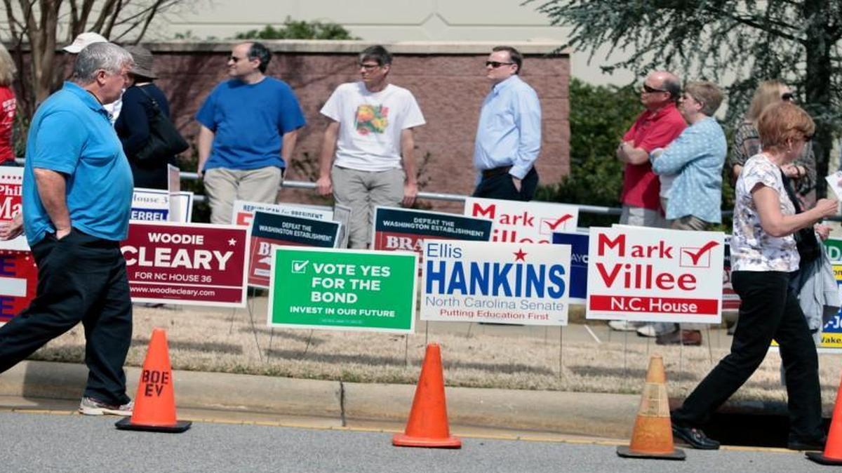 Two Wake county voters in foreground leave the early voting precinct while others wait in line to vote, background, outside of the Herbert C. Young Community Center early voting site in Cary, NC Friday, March 11, 2016.