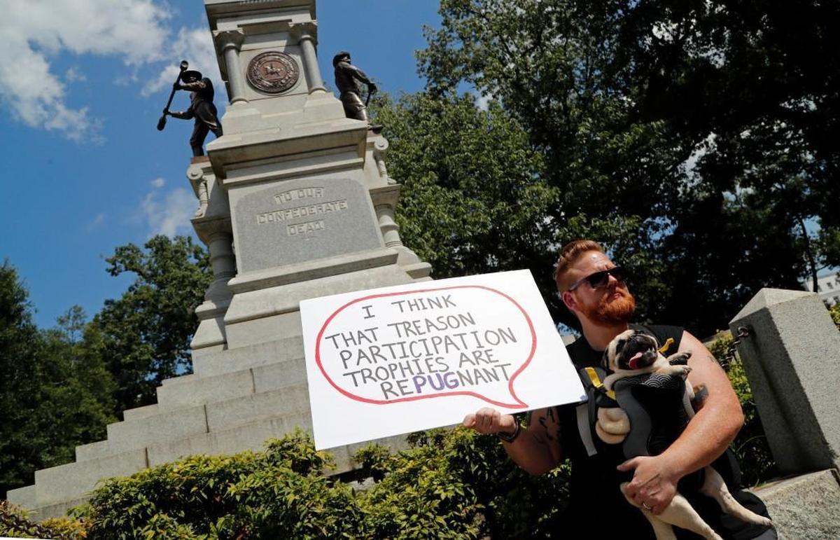Thor Dollar from Raleigh holds his pug Loki as he gives his views about whether Confederate monuments should be removed from the N.C. Capitol grounds in Raleigh, NC on Aug. 16, 2017. He thinks this one should be removed, adding that maybe its place should be in a museum. Gov. Roy Cooper called for the removal of Confederate monuments on state grounds.