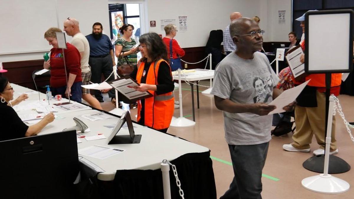A Wake county voter, right, moves toward the voting booth after obtaining his ballot at the Herbert C. Young Community Center early voting site in Cary March 11, 2016.