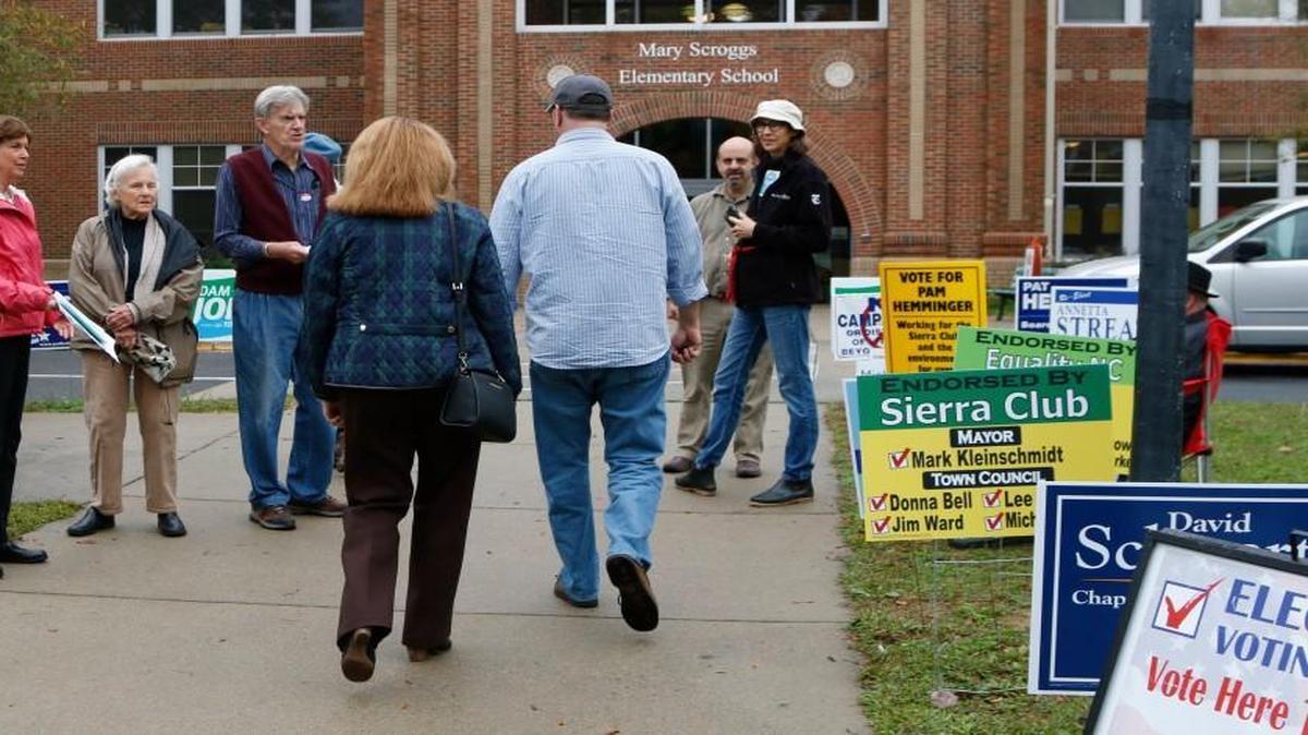 Two voters at center have to walk the gauntlet of campaign workers for area candidates and issues as they go to vote at Mary Scroggs Elementary School in Chapel Hill, NC Tuesday, November 3, 2015.