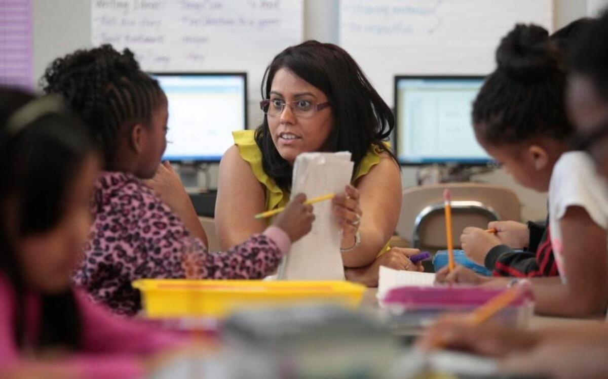Barwell Road Elementary school teacher Yolanda Roman, center, focuses her attention on a 2nd grader in her math class learning how to subtract with 10s and 100s during Roman's homeroom March 17, 2016.
