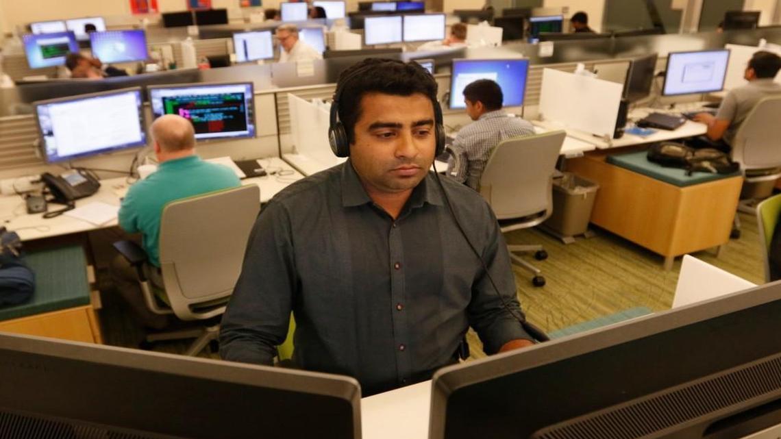 Fidelity Investments/RTP senior software engineer Jovin Manayath listens in on a conference call while he monitors his system at his standing workstation Oct. 27, 2015. Earlier that day, financial services firm Fidelity Investments had announced that it would create 600 new jobs, mostly in IT and related fields, in its Cary, NC, and Durham, NC, offices within three years.